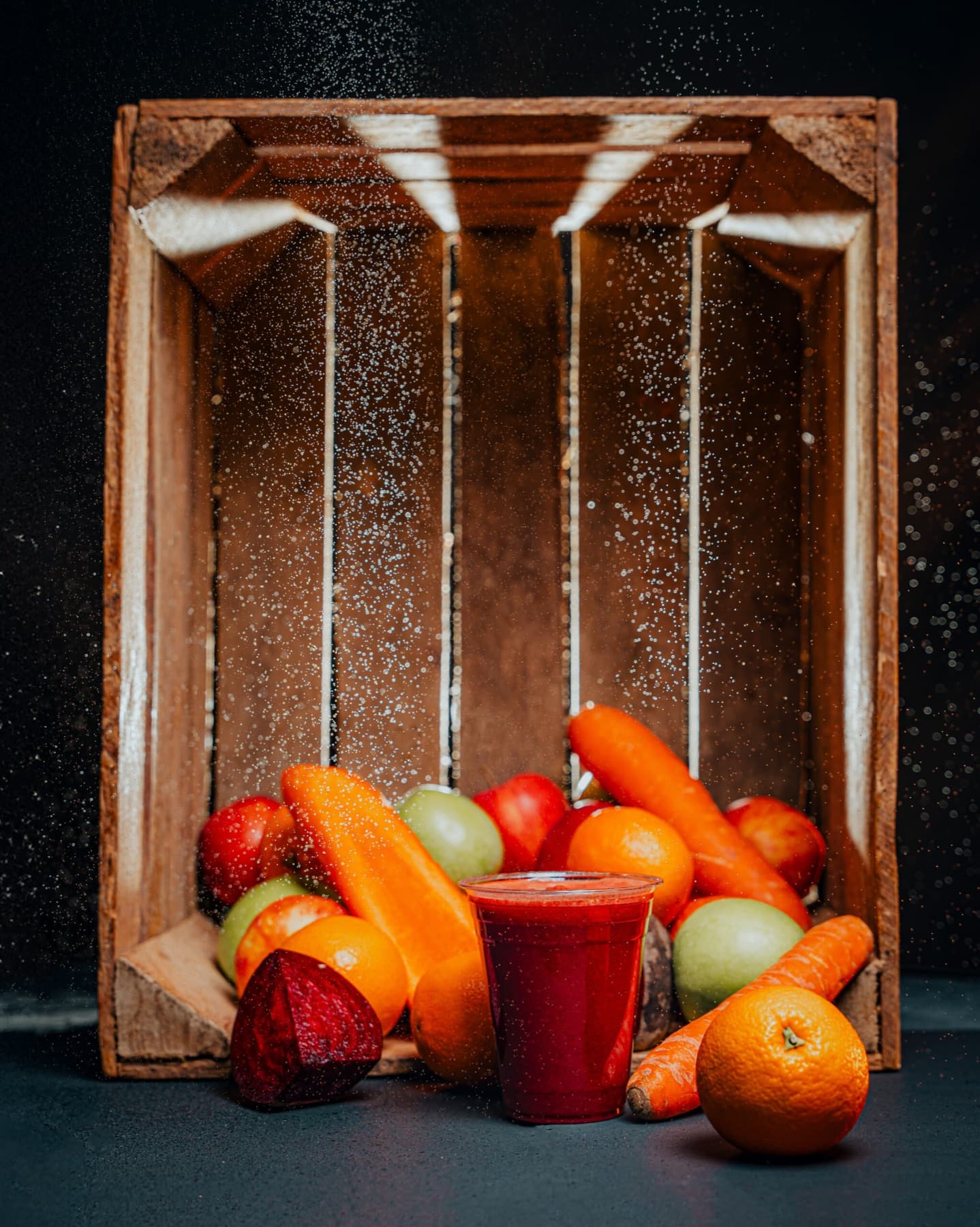 A clear cup of deep-red Classica juice on a charcoal-and-wood studio set.