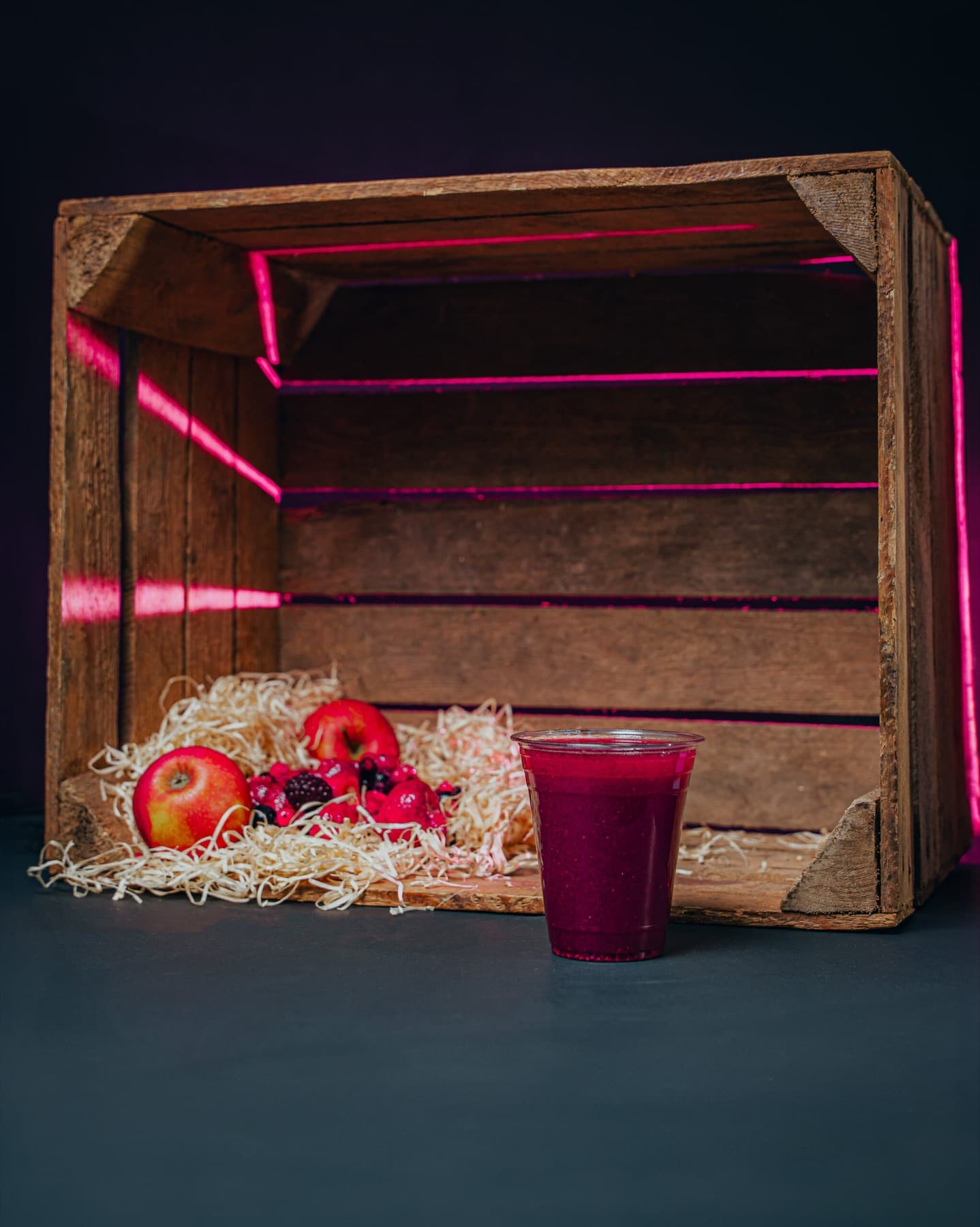 A clear cup of deep berry-red mixed berry juice against a dark studio background.