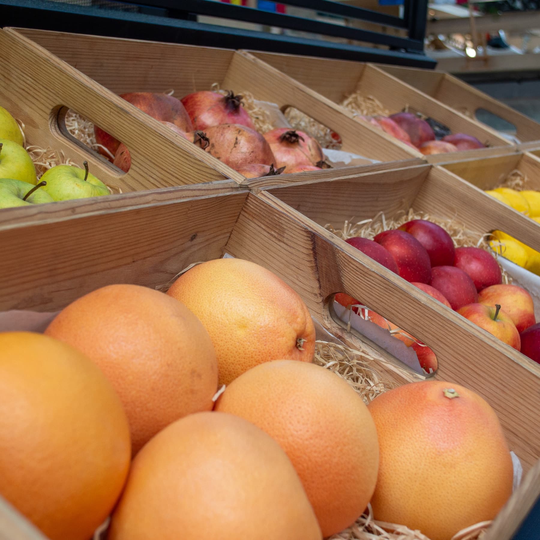Wooden market crates of fresh grapefruit, apples and pomegranates at the Juice Guys stall.